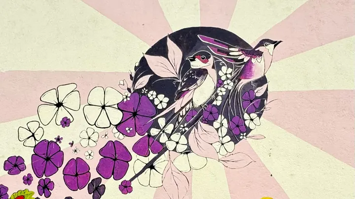 Mural of a bird among purple and white flowers on a pale pink sunburst