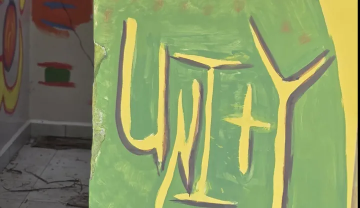 Green mural with hand-painted yellow UNITY lettering