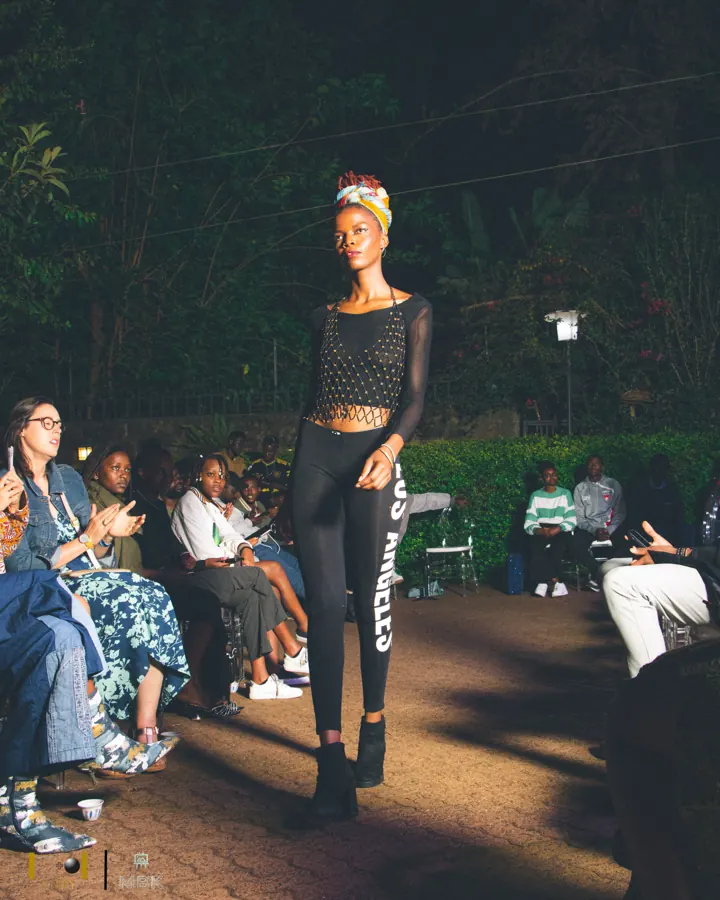 Model on a night runway in a black mesh top, black leggings and a colourful headwrap