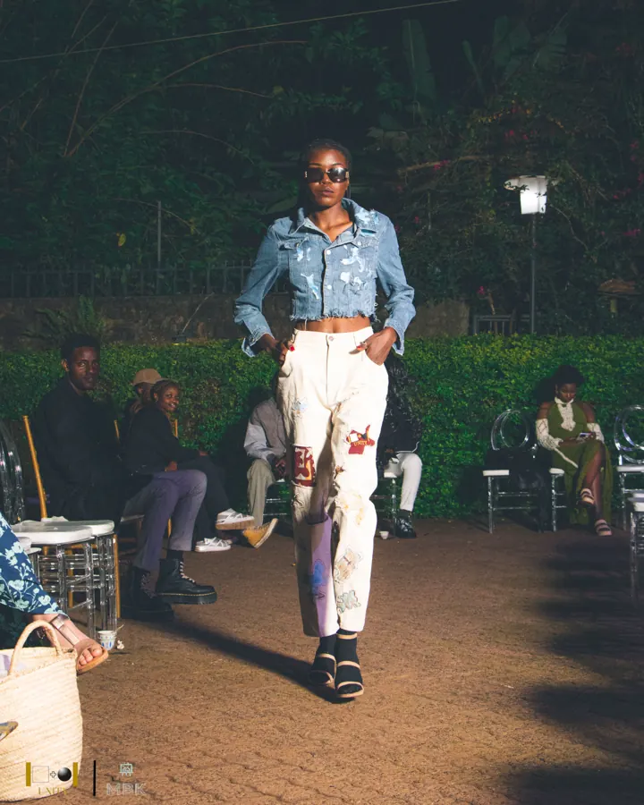 Model on a night runway in a cropped denim jacket and painted white jeans